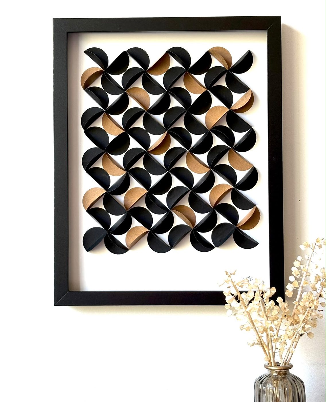 Framed paper wall piece of black and gold pinwheel circles