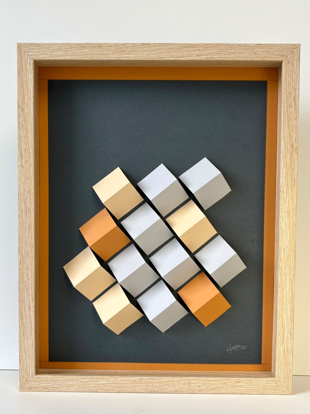 Framed 3D cube wall piece in a diagonal orange, grey and cream pattern