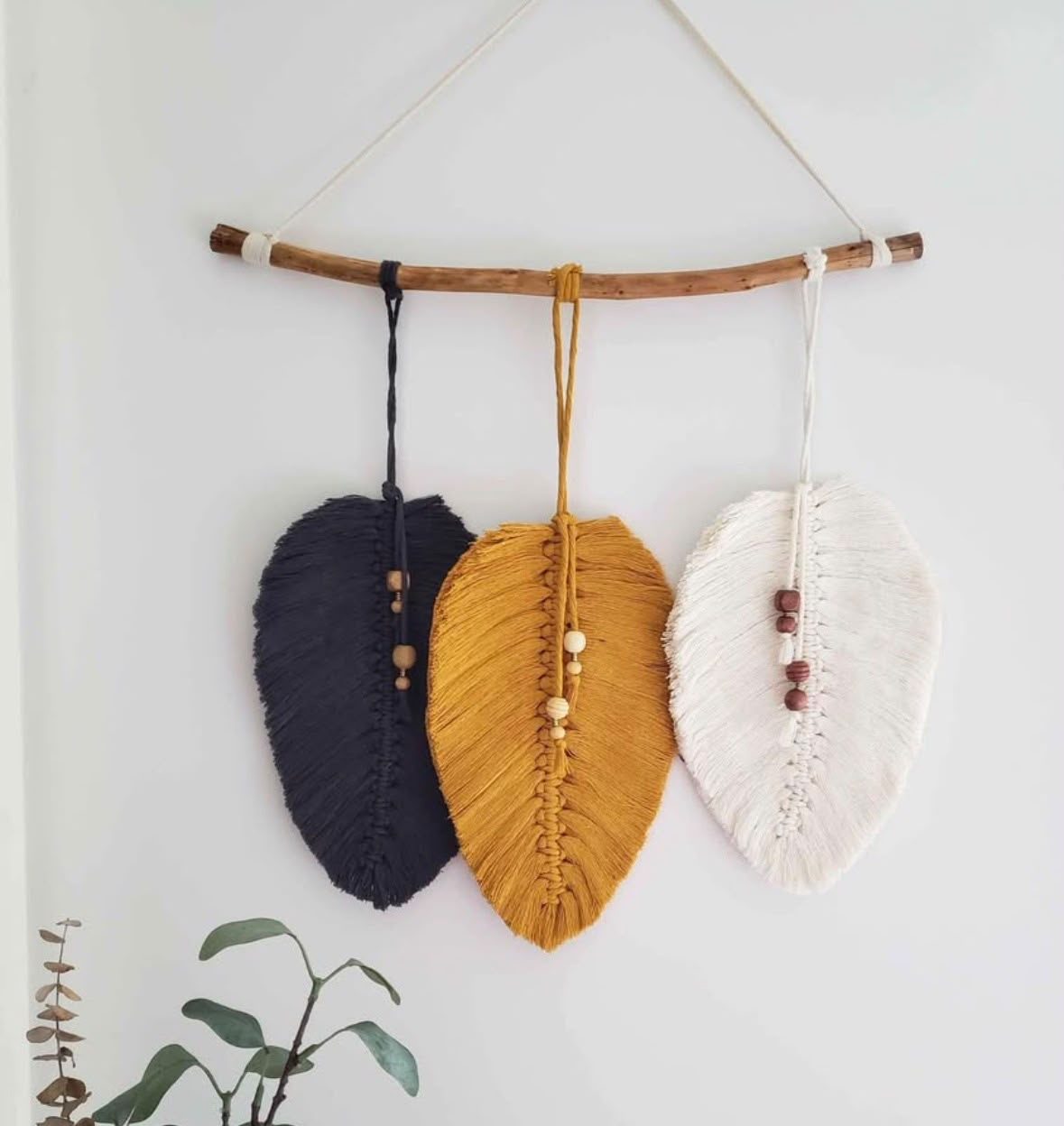 Three fiber leaf shapes hanging from a branch