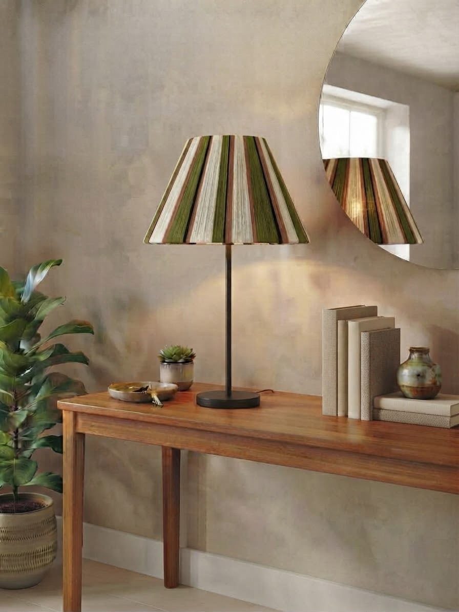 Lamp with a striped green, cream and rust shade, reflected in a round mirror