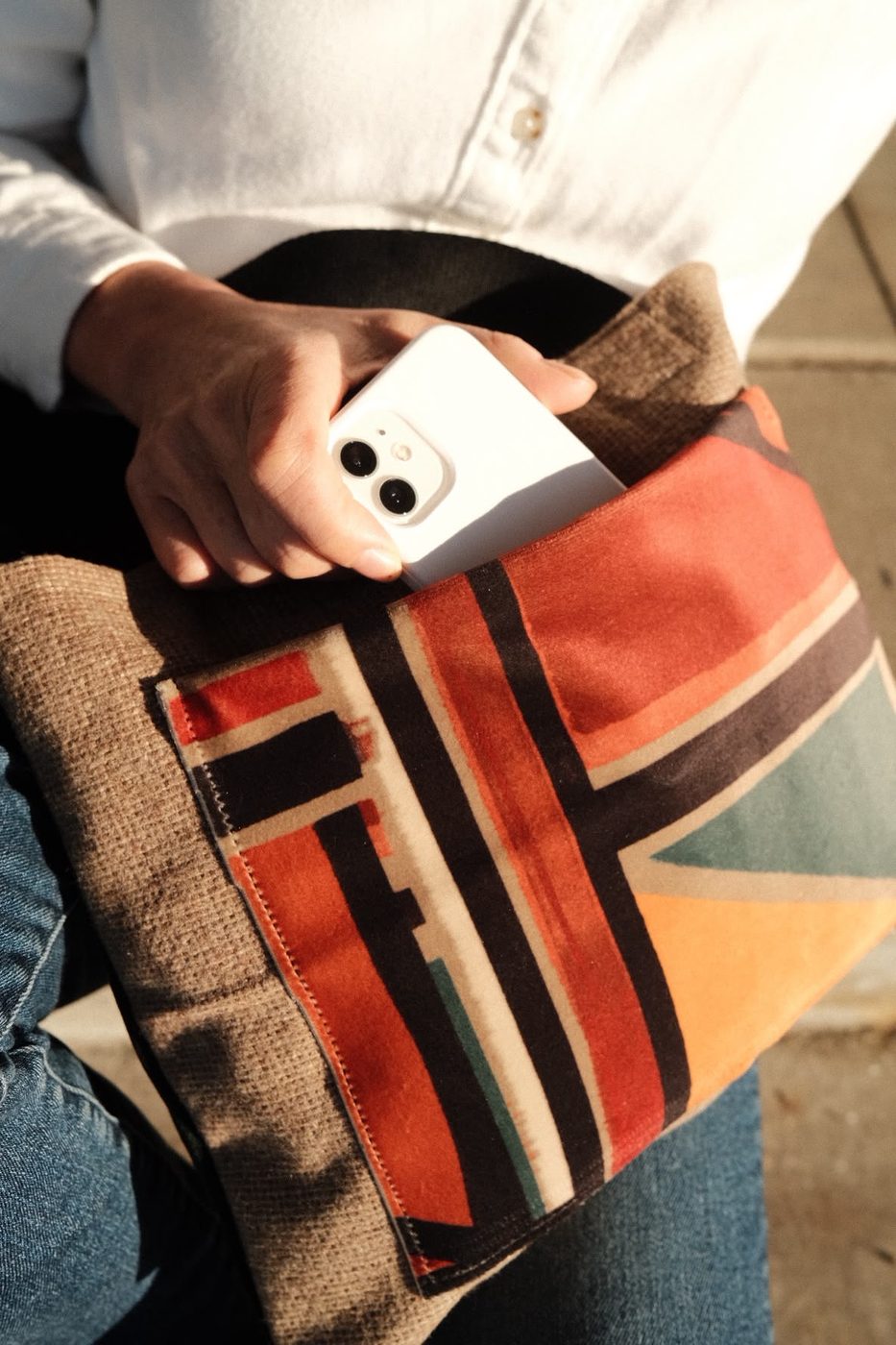 Hand holding a patchwork pouch in striped suede and linen