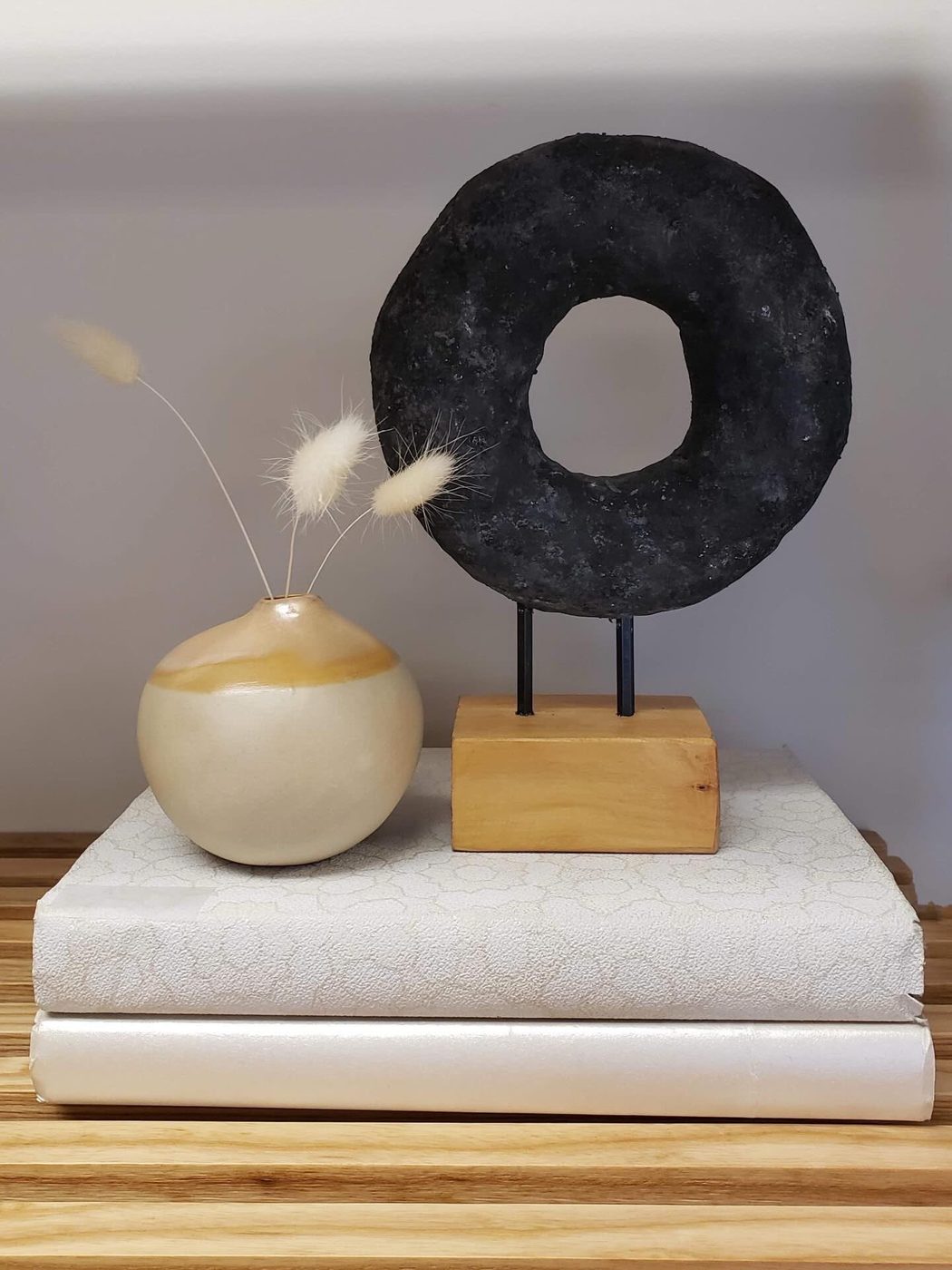 Still life of a vase and a black stone ring on books