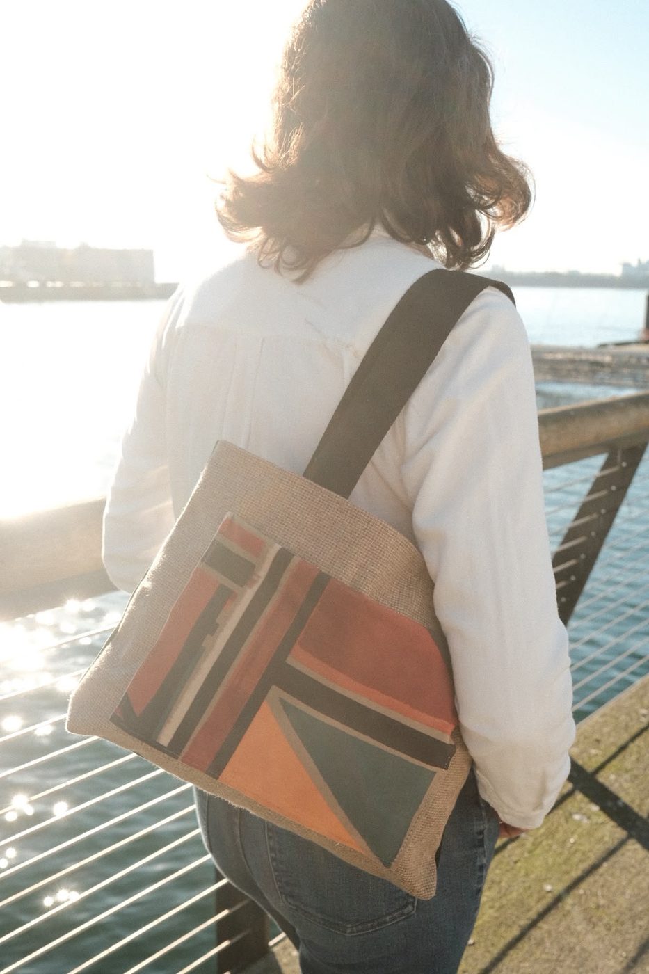 Woman carrying a geometric woven tote on the waterfront