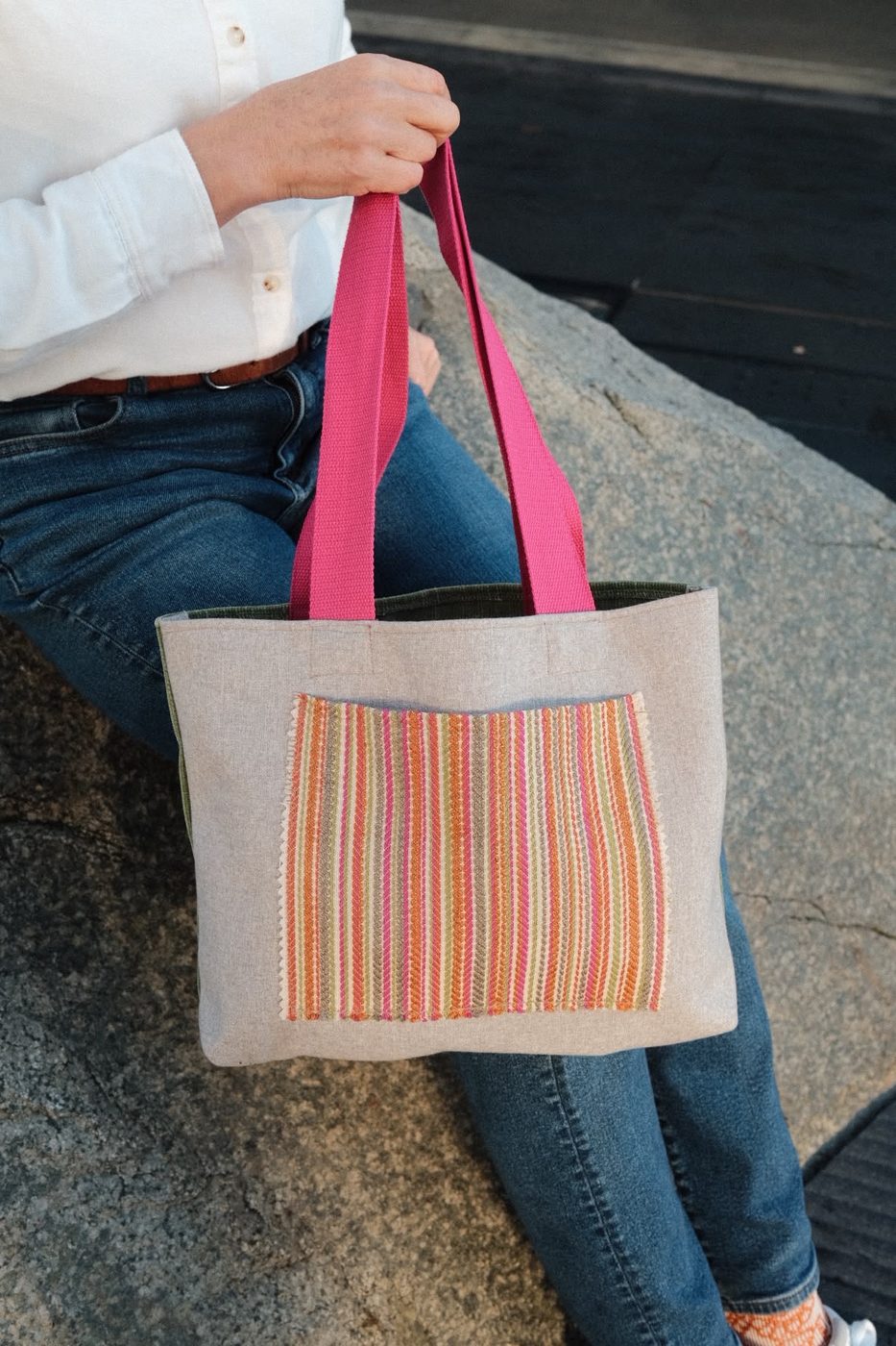 Detail of an orange pocket tote held in hand